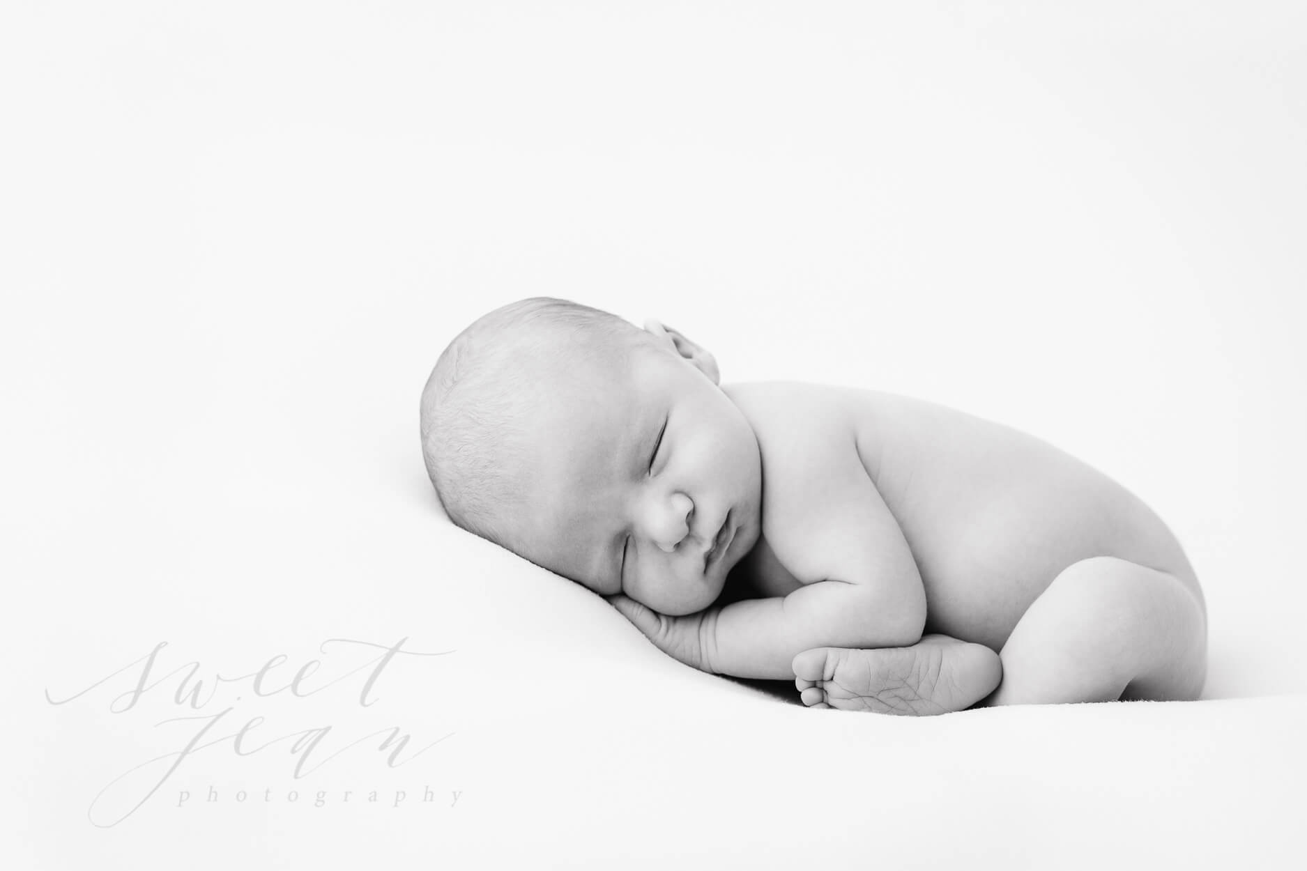 Newborn baby boy sleeping on white sweet jean photography