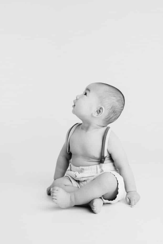 Baby boy in shorts with suspenders by Roseville Baby Photographer Sweet Jean Studio.