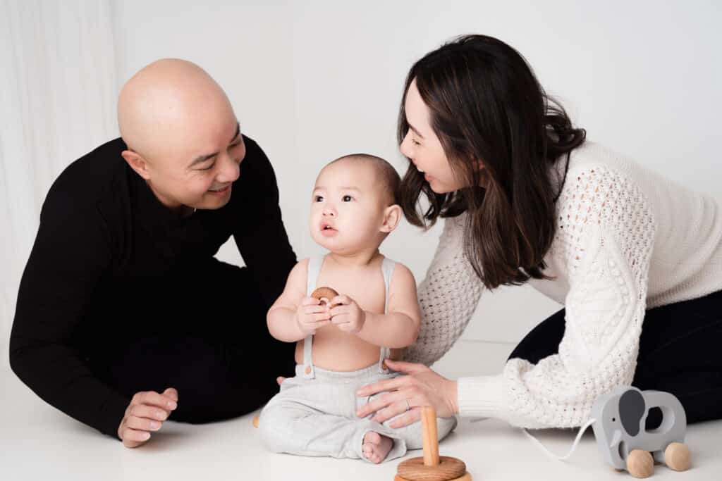 Mom, dad and baby playing with wooden toys.